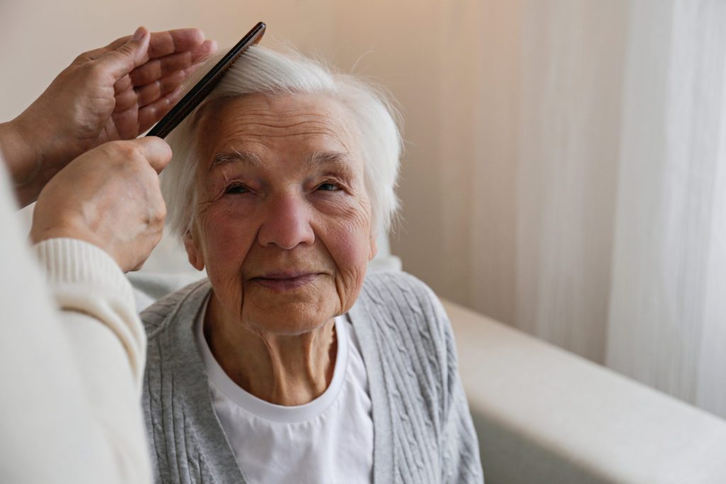 Hospice worker combing womans hair