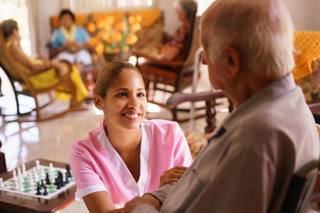 Hospice worker kneeling in front of patient smiling